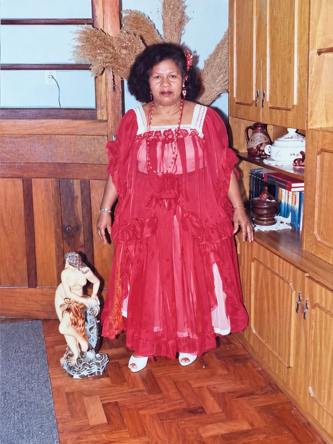 A muana oya (mulher) de pé vestida de vermelho